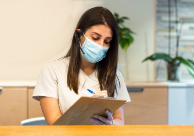 receptionist-taking-notes-on-clipboard-at-medical-center