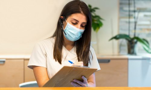 receptionist-taking-notes-on-clipboard-at-medical-center